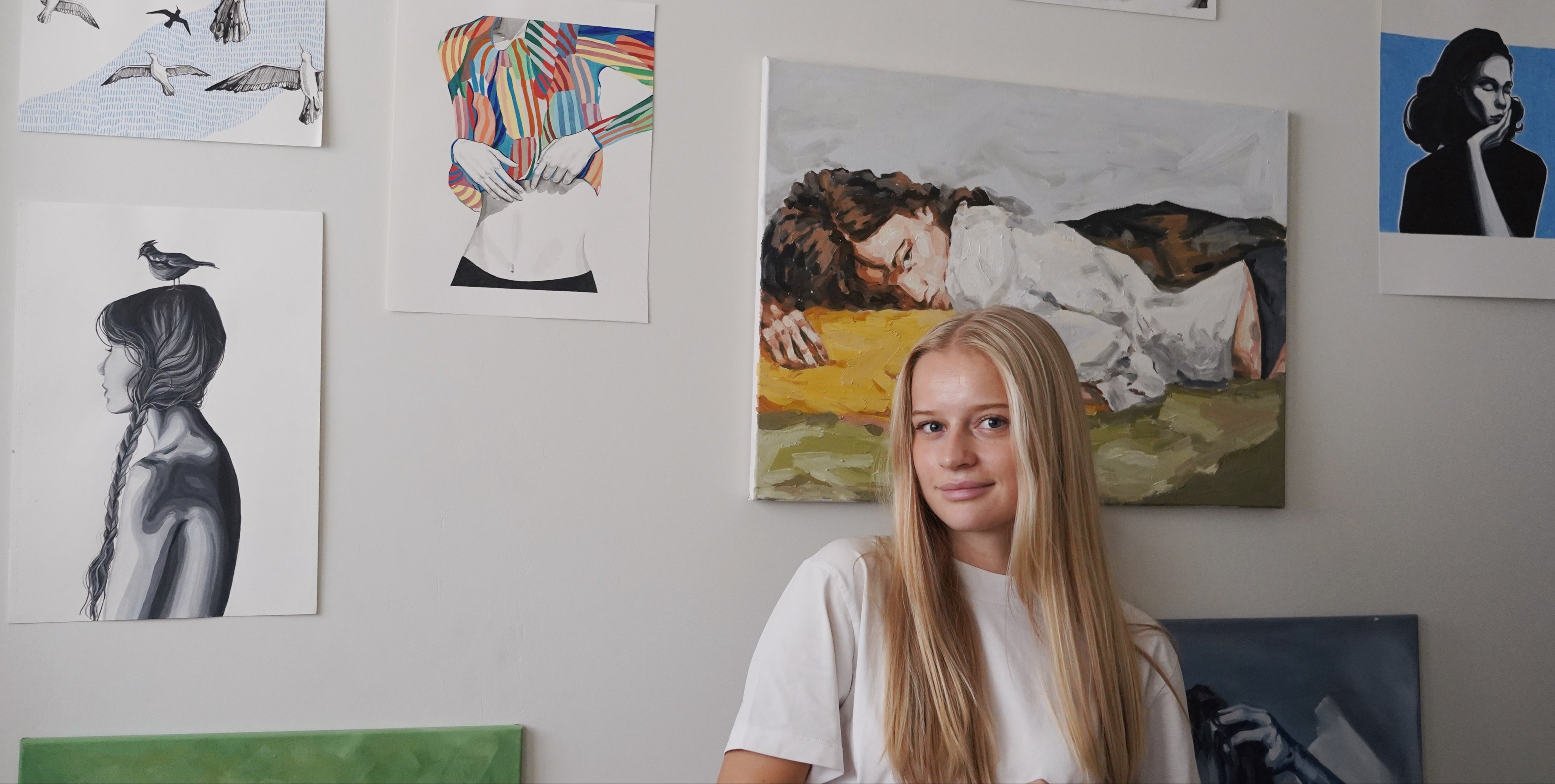 Woman sitting in front of a wall with various artworks